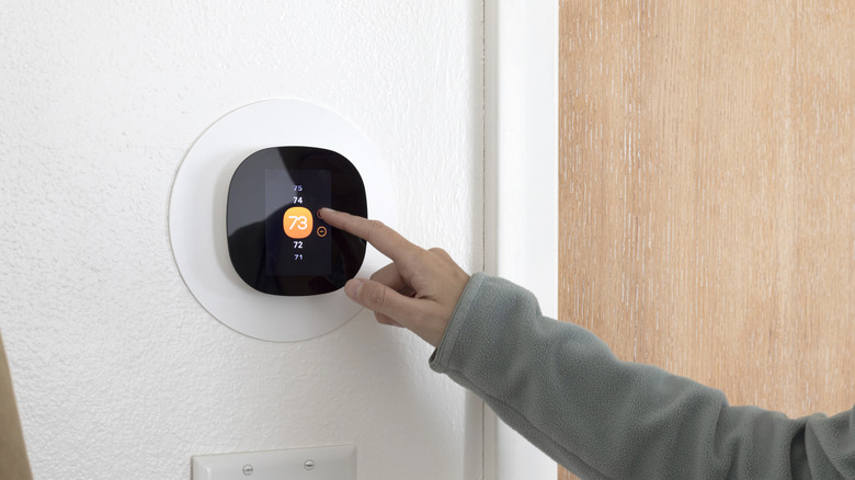 Person adjusting smart thermostat