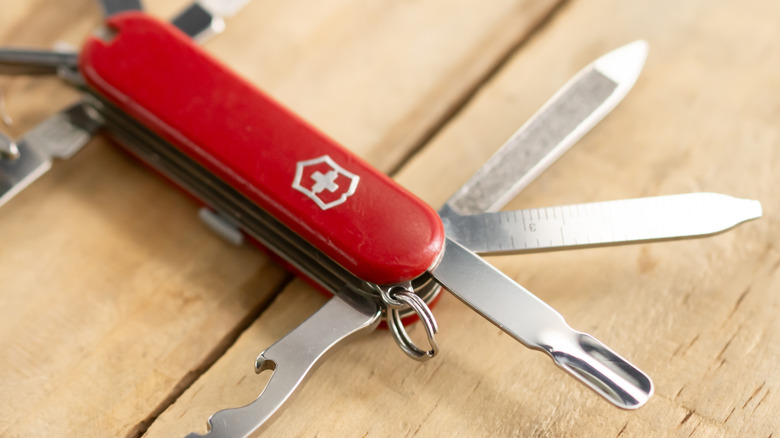 A Swiss Army Knife with multiple tools open on top of a wood table
