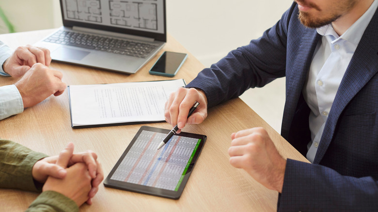 People using a tablet with a laptop in the background