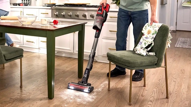 Perso using Craftsman Stick Vacuum to clean a kitchen mess