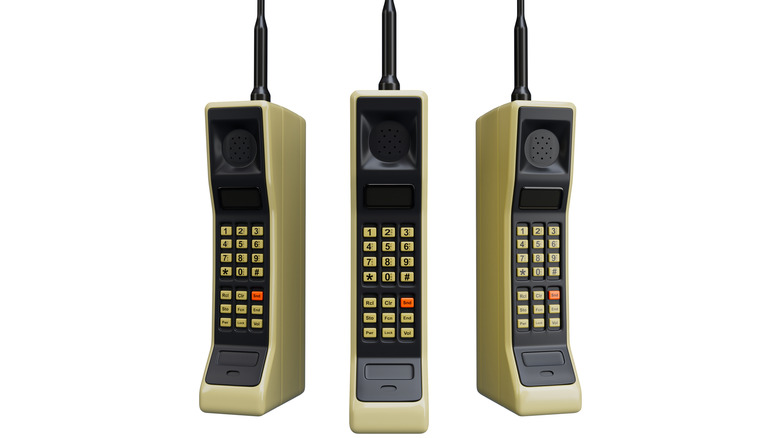 Three Motorola DynaTAC phones side-by-side with number pads facing camera