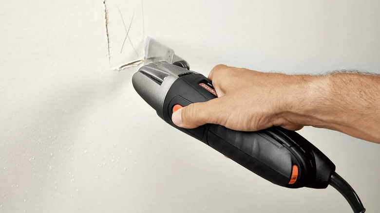 Man using Warrior oscillating tool to cut drywall