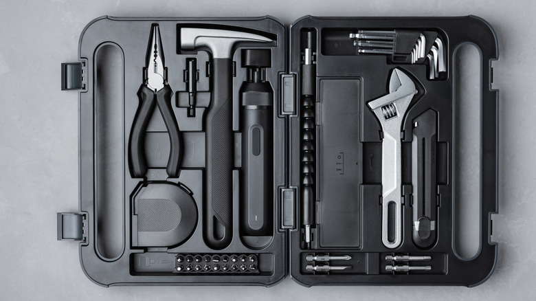 A black toolbox open with multiple tools inside it