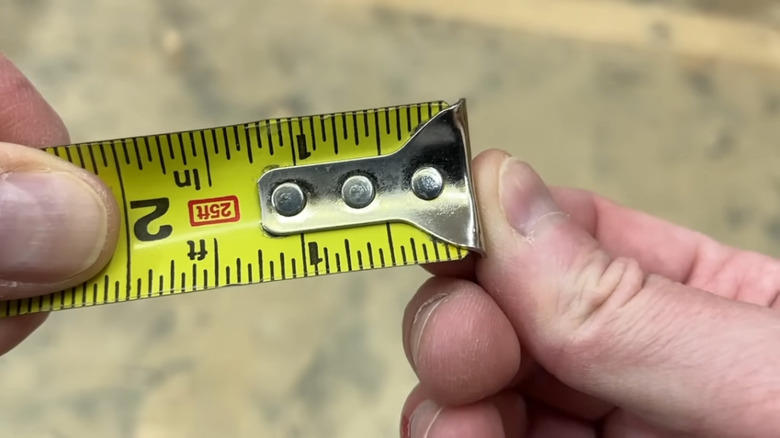 The Honest Carpenter holding the tab on a tape measure