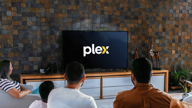 People gathered around a TV showing the Plex logo
