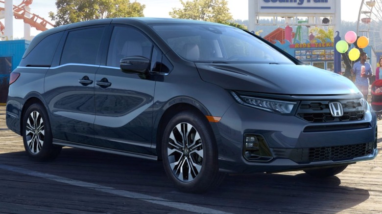 A 2026 dark gray Honda Odyssey is parked on a lively boardwalk near a county fair.