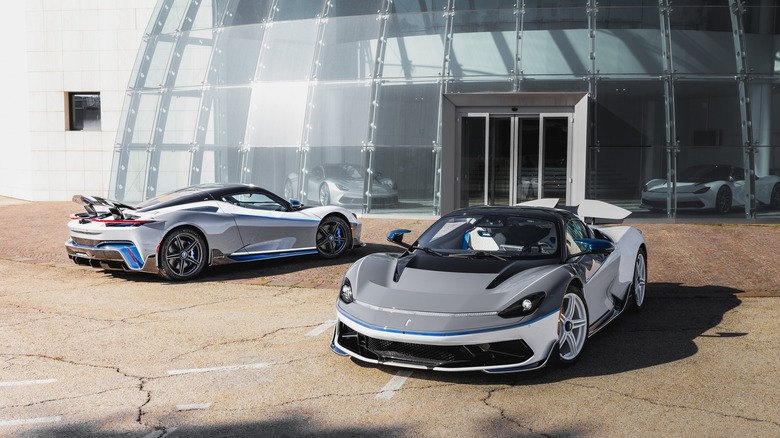 Two Pininfarina Battista cars parked in front of Pininfarina showroom, front and rear-right three-quarter views