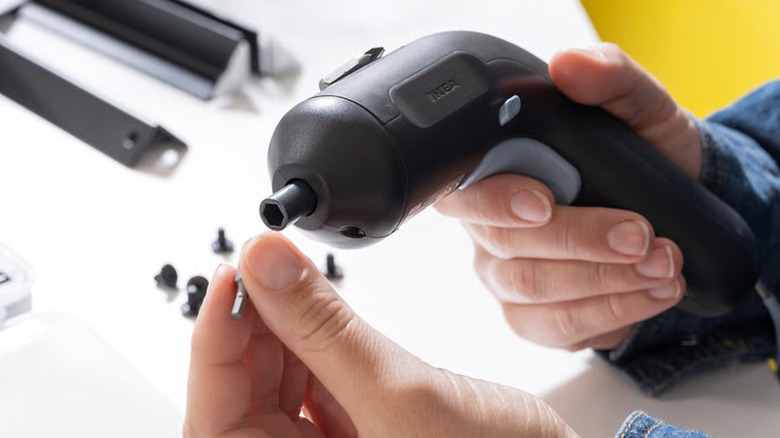 A person putting a drill bit in an Ikea cordless screwdriver