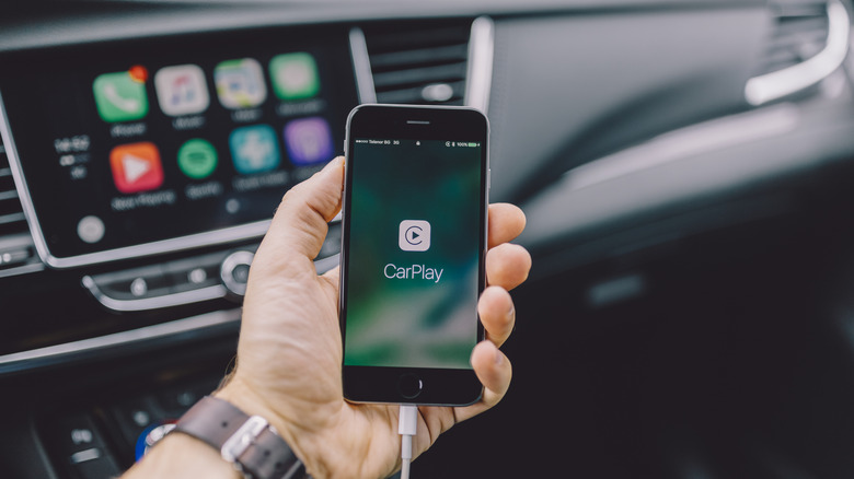 Person holding iPhone with CarPlay logo