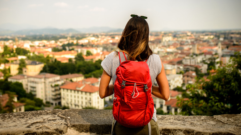 woman with red backpack overlooking small city