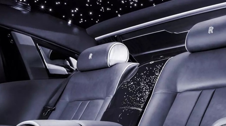 Interior of Rolls-Royce vehicle with black leather seats and starlights on the ceiling