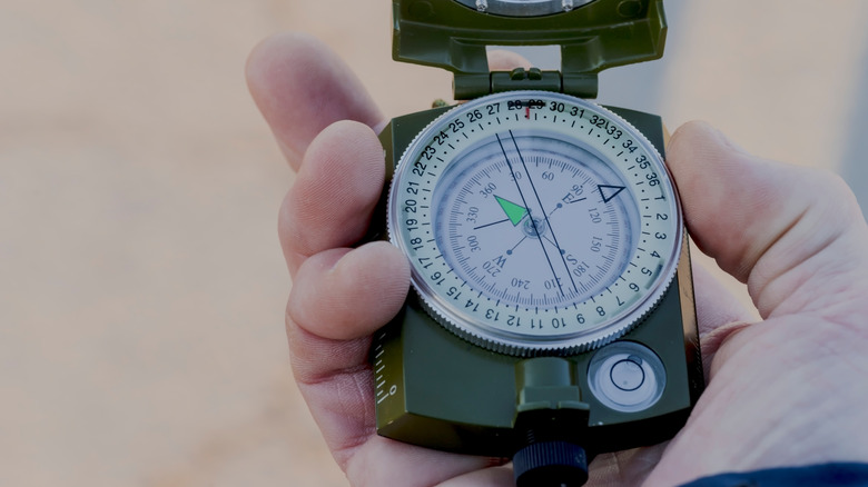 Man holding a compass while in the outdoors