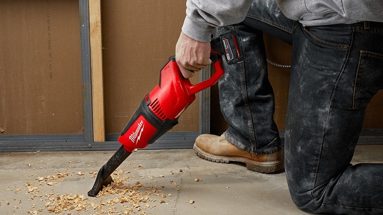 Person cleaning floor with Milwaukee M12 Compact Vacuum