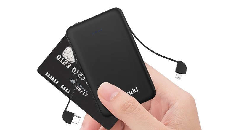 A hand holds a black power bank as big as credit card.