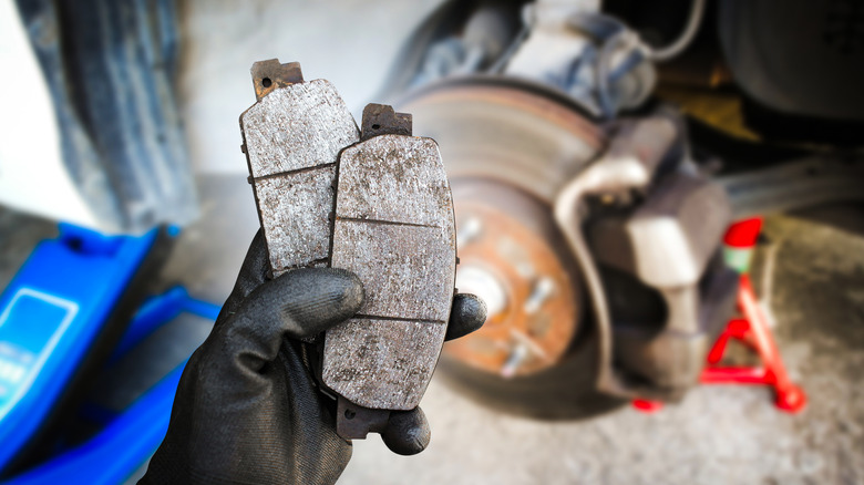 Used brake pads in a mechanic's hand