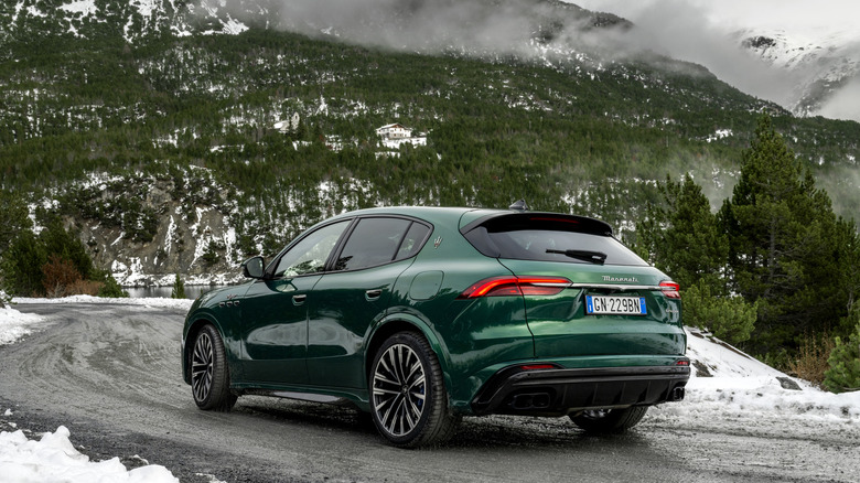 Green Maserati Grecale Trofeo SUV seen from left rear on snowy mountain road