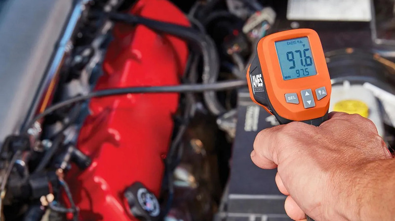 An orange laser thermometer by Ames Instruments used on a car engine