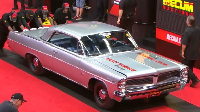 Men pushing a 1963 Pontiac "Swiss Cheese" Catalina Super Duty at Mecum Indy 2025