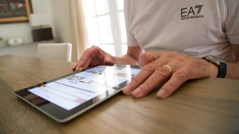 man sitting at table, reading something on older generation iPad.