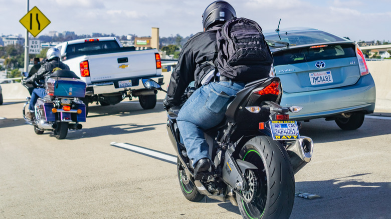Motorcycle riders splitting lanes next to cars
