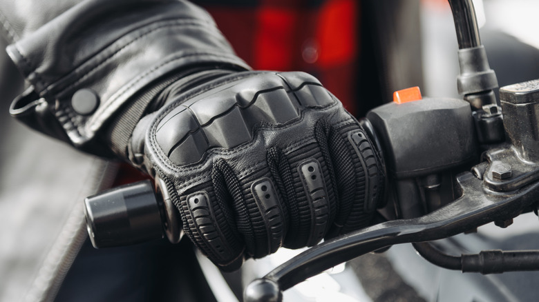 A man wearing gloves with his hands on the accelerator of a motorcycle