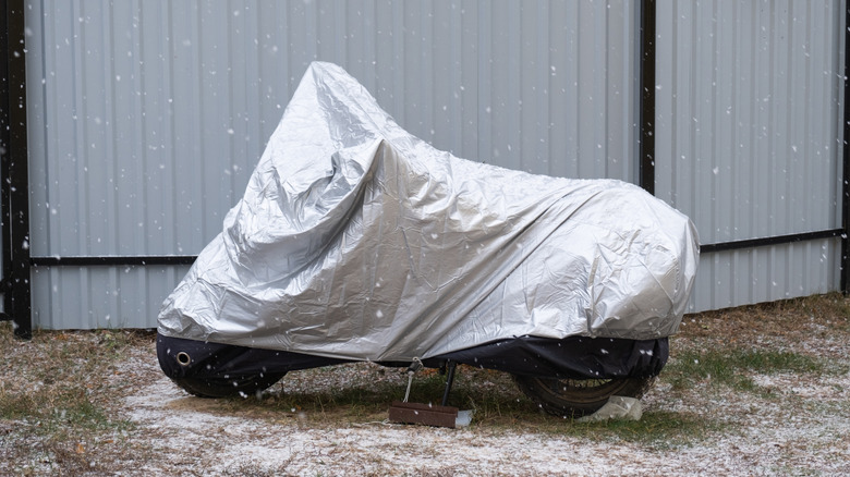 A motorcycle parked with motorcycle cover indoors during winter