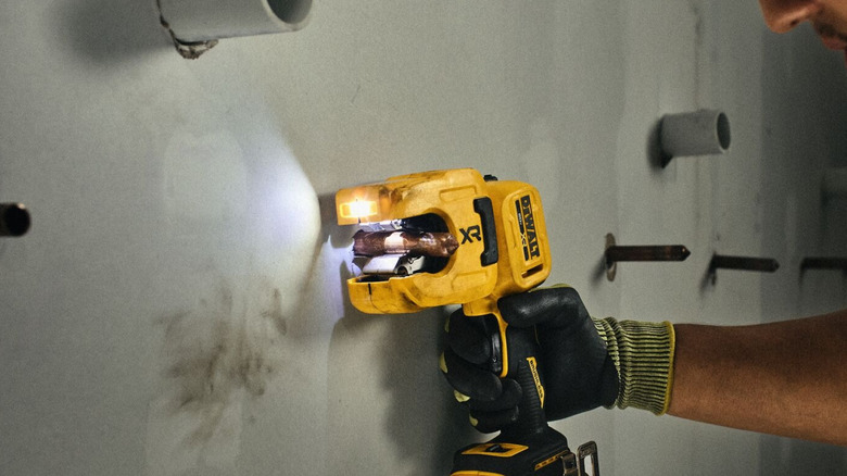 DeWalt 20V Max XR 1-1/4 Inch Copper Tubing Cutter cutting a pipe from a wall