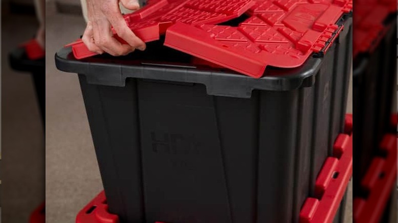 Person openening lid of HDX 27-Gallon Flip-Top Tote