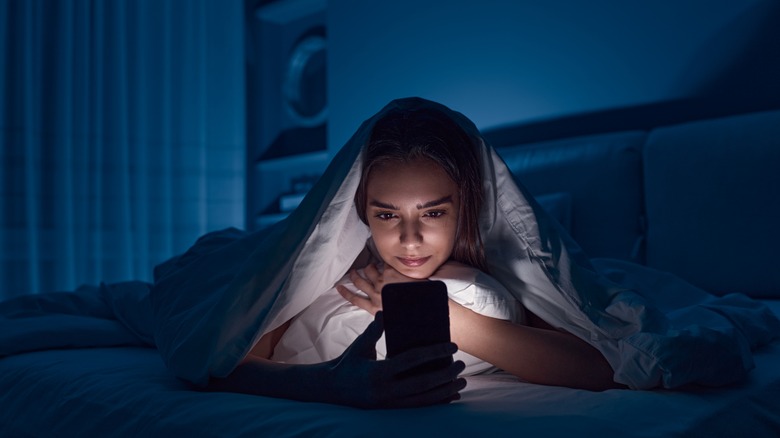 Woman watching movie on phone in bed