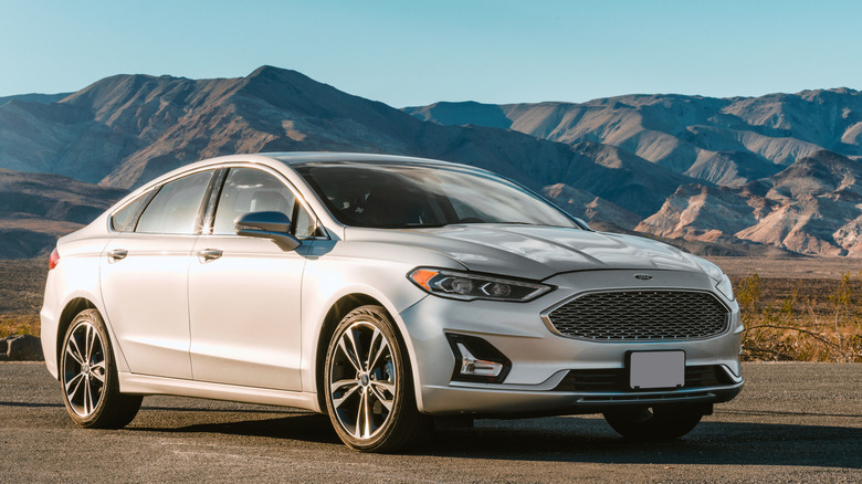 A silver 2018 Ford Fusion parked in front of a mountain range.