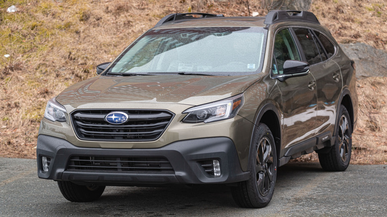 A brown 2021 Subaru Outback parked in front of a hill.