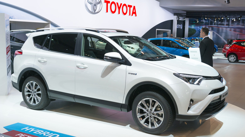 A white Toyota RAV4 hybrid on display at an auto show.