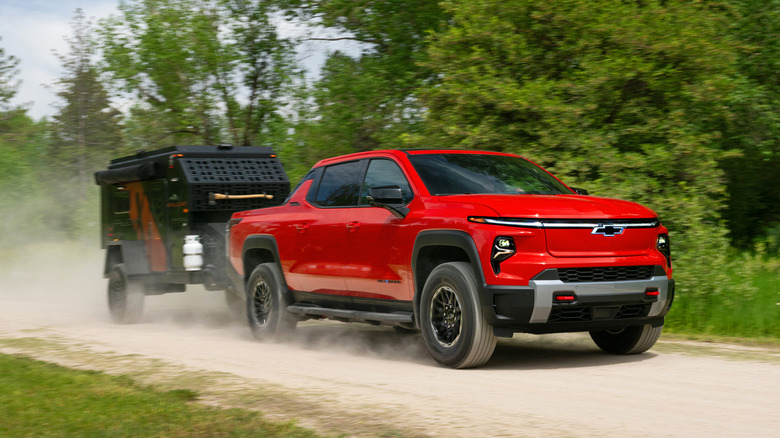 A red 2026 Chevrolet Silverado EV towing