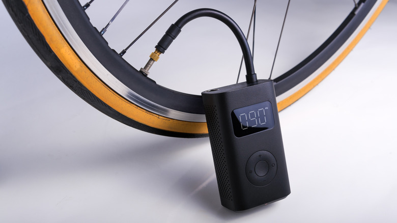 A brandless portable electric air pump being used on a bike tire