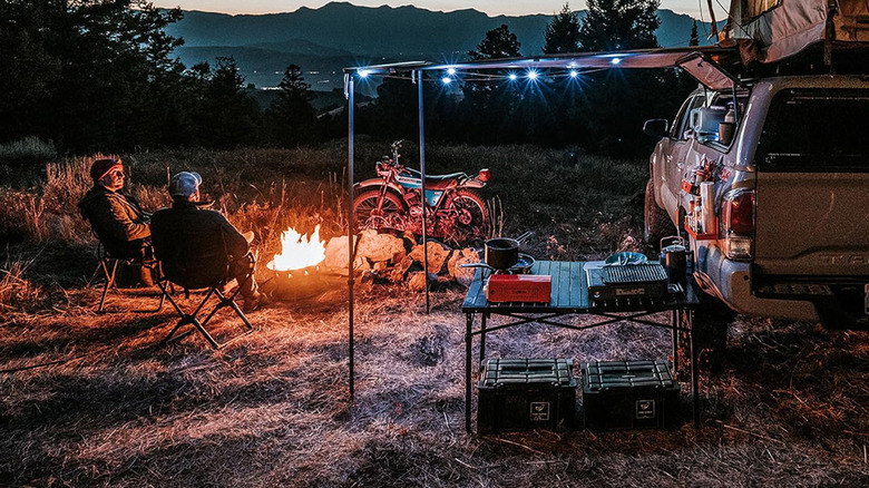 A camping space with a campfire and a truck with string lights