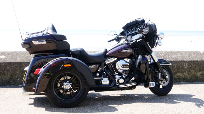 A black Harley-Davidson Tri Glide ultra parked by a seawall in the UK