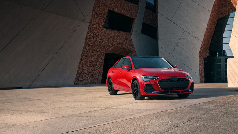 A red Audi A3 parked next to an artsy building
