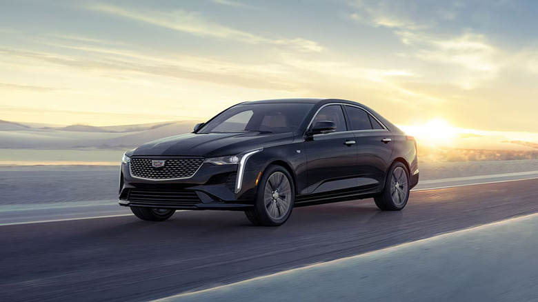 A Cadillac CT4 driving on a snowy road at sunset