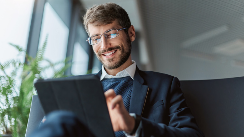Smiling man sitting down and using tablet