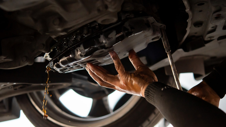 Mechanic draining automatic transmission fluid