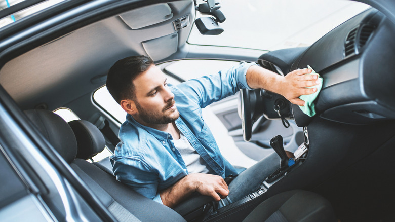 man cleaning dashboard of car