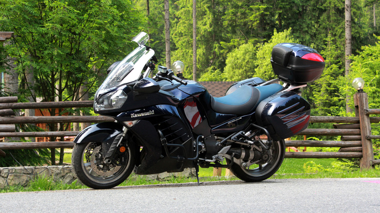 A black Kawasaki 1400 GTR parked next to a road on a sunny day