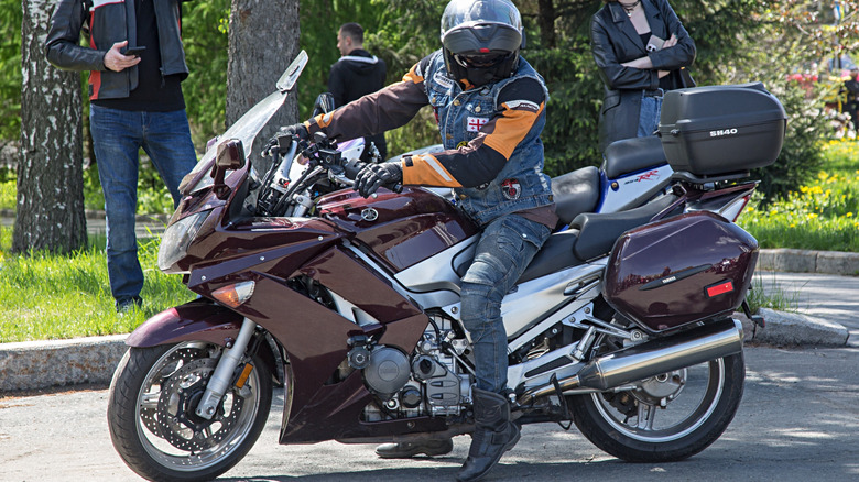 A biker on dark cherry Yamaha FJR1300 with trees in the background