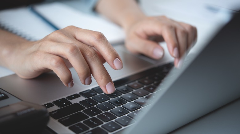Close up of hand typing on laptop