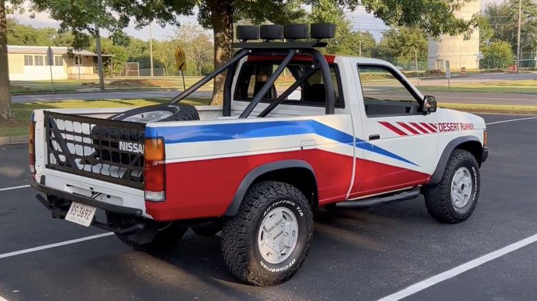 A 1988 Nissan Desert Runner truck parked in a parking lot with trees and grass in the background.