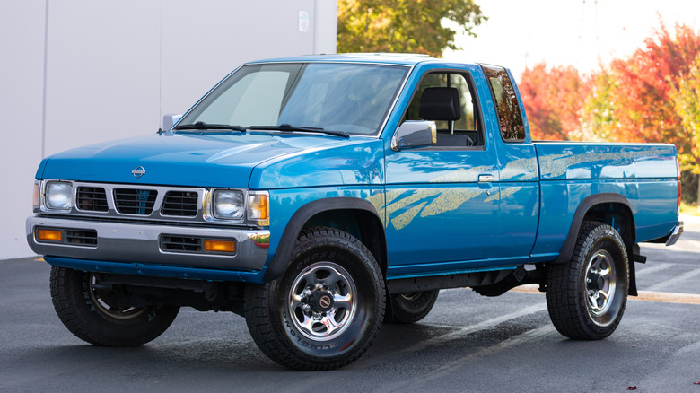 An old 1980s blue Nissan truck with white stripes.