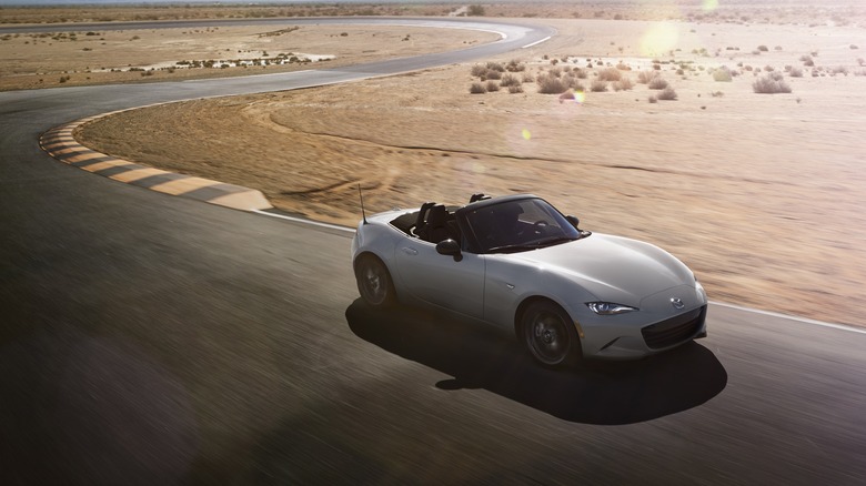 White Mazda MX-5 Miata driving around a circuit, front-right aerial view