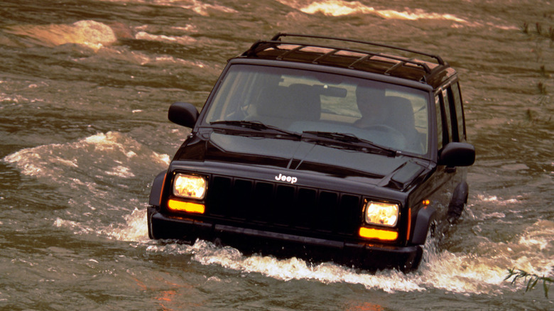 Black 1997 Jeep Cherokee driving through axle-deep water, front-view