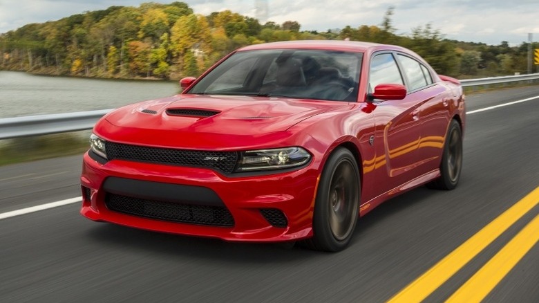 2015 Dodge Charger SRT Hellcat driving on a road with trees and water body in the background