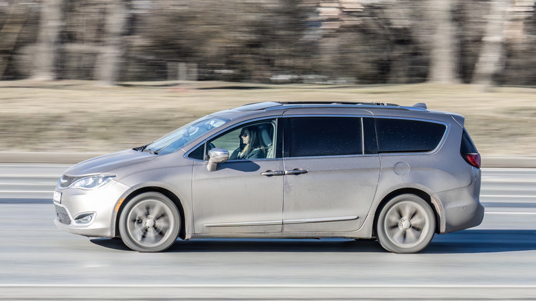 Driver side view of gray minivan driving on highway